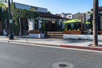 a city sidewalk with benches and tables at an intersection in a town setting at a business