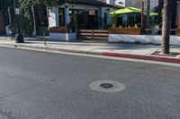 a city sidewalk with benches and tables at an intersection in a town setting at a business