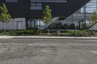 a building has several plants on either side and a bus driving down the street in front