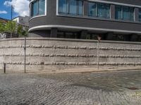 a cobblestone street next to two buildings with street signs on them, on a partly cloudy day