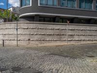 a cobblestone street next to two buildings with street signs on them, on a partly cloudy day