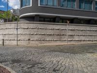 a cobblestone street next to two buildings with street signs on them, on a partly cloudy day