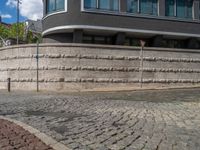 a cobblestone street next to two buildings with street signs on them, on a partly cloudy day