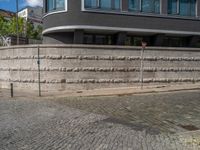 a cobblestone street next to two buildings with street signs on them, on a partly cloudy day