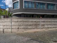 a cobblestone street next to two buildings with street signs on them, on a partly cloudy day