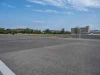 there is an empty parking lot in the day time, on a sunny day with a blue sky and small clouds