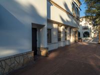 a street with two buildings and a fire hydrant in the middle of it, next to a stone walkway with some trees