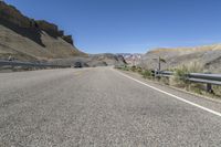 the road is empty and winding in to the desert area near some rocks and hills