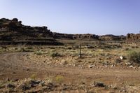 a large brown hill with a small rock outcropping near it and some dirt road