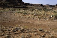 a large brown hill with a small rock outcropping near it and some dirt road