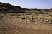 a large brown hill with a small rock outcropping near it and some dirt road