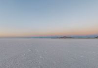 the desert is full of footprints of people in the snow at sunset outside of the mountains