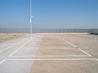 a empty parking lot with an antenna on top and blue sky above it, next to some metal fences