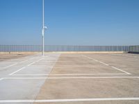 a empty parking lot with an antenna on top and blue sky above it, next to some metal fences