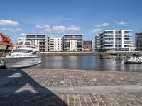 boats docked at the end of the waterfront in an urban setting with other apartment buildings on the side