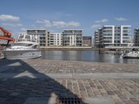 boats docked at the end of the waterfront in an urban setting with other apartment buildings on the side