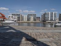 boats docked at the end of the waterfront in an urban setting with other apartment buildings on the side