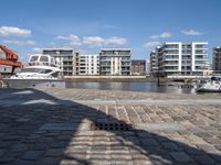 boats docked at the end of the waterfront in an urban setting with other apartment buildings on the side