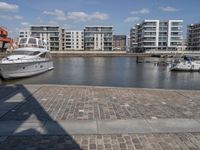 boats docked at the end of the waterfront in an urban setting with other apartment buildings on the side