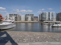 boats docked at the end of the waterfront in an urban setting with other apartment buildings on the side