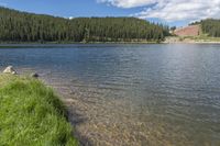 a man fly fishing at the edge of a lake with his poles attached to a pole