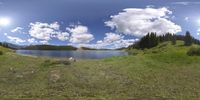 a panorama fisheye view looking down on the lake and trees in the distance with clouds