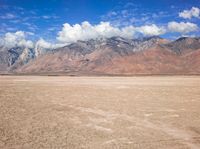 a plane sitting on top of a sandy beach near a mountain range surrounded by clouds