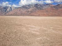 a plane sitting on top of a sandy beach near a mountain range surrounded by clouds