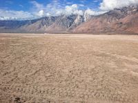 a plane sitting on top of a sandy beach near a mountain range surrounded by clouds