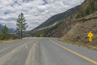 a paved road winds its way up the side of a mountain with mountains and pine trees