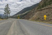 a paved road winds its way up the side of a mountain with mountains and pine trees