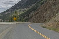 a paved road winds its way up the side of a mountain with mountains and pine trees