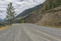 a paved road winds its way up the side of a mountain with mountains and pine trees