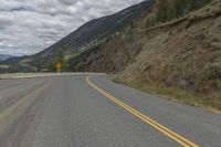 a paved road winds its way up the side of a mountain with mountains and pine trees