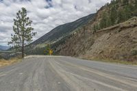 a paved road winds its way up the side of a mountain with mountains and pine trees