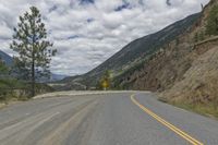 a paved road winds its way up the side of a mountain with mountains and pine trees