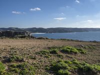 a dirt path leading to the shore line on the beach in the foreground is the coast