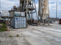 a group of three fire trucks are sitting in a lot next to a tall concrete silo