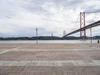 a view of the river and bridge from a bench near it, with no people on the sidewalk