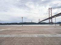 a view of the river and bridge from a bench near it, with no people on the sidewalk