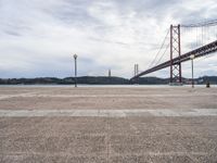 a view of the river and bridge from a bench near it, with no people on the sidewalk