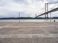 a view of the river and bridge from a bench near it, with no people on the sidewalk