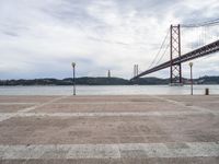 a view of the river and bridge from a bench near it, with no people on the sidewalk