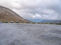 an empty parking lot with two vehicles parked beside the road and mountain range in the distance