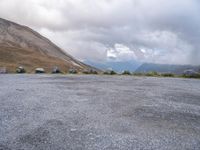 an empty parking lot with two vehicles parked beside the road and mountain range in the distance