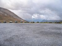 an empty parking lot with two vehicles parked beside the road and mountain range in the distance