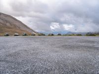 an empty parking lot with two vehicles parked beside the road and mountain range in the distance