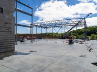 people standing around near the unfinished building under construction on a partly sunny day at the intersection of a road