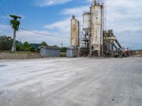 a cement plant with two trucks parked in the lot near it and palm trees on either side