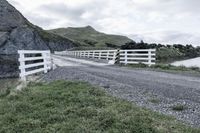 there is a road that runs through a rocky valley with a fenced in area